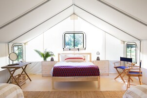 Una habitación con carpa que incluye una cama, un escritorio, una silla y una ventana.