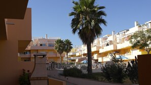 Un edificio residencial con varios balcones, palmeras y un patio empedrado.