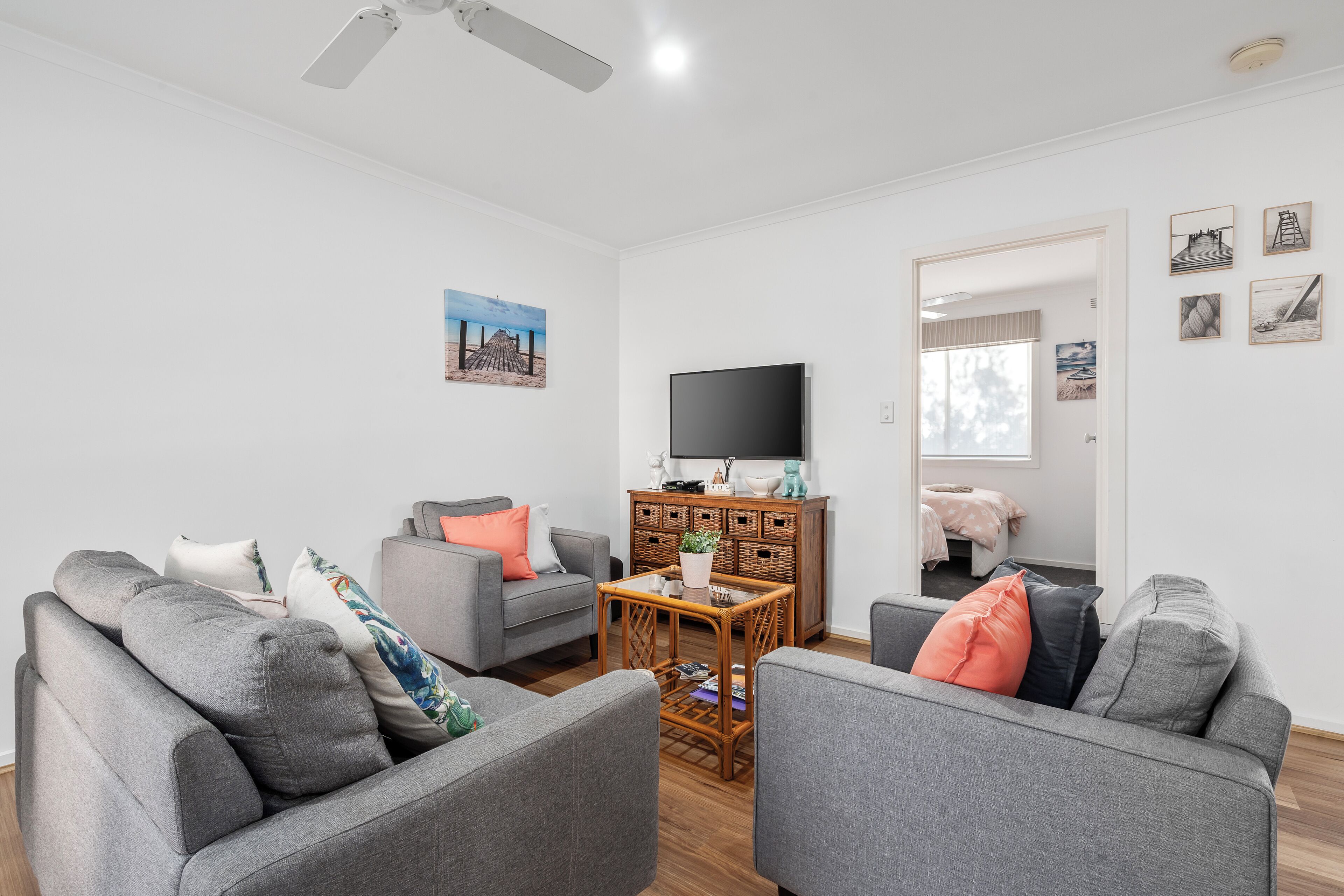 A modern living room with grey sofas, a wooden coffee table, and a flat-screen TV.