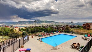 Una piscina con sillones de descanso y vistas a montañas al fondo.