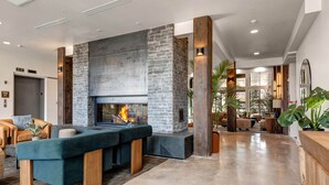 Una sala de estar moderna con chimenea de piedra, asientos cómodos y vista al área de comedor.