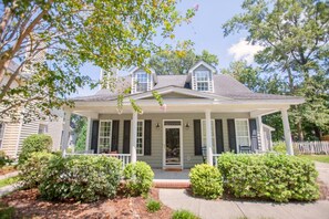 A two-story house with a front porch, a small front yard, and a picket fence.