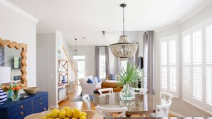 Een lichte eetruimte met een ronde tafel, witte stoelen en een kroonluchter.