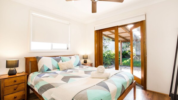 A bedroom with a bed, bedside tables, a window, and a view of the outdoors.