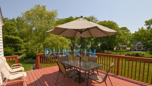 A wooden deck with a glass table and chairs, an umbrella, and a sign that reads "DURKIN".