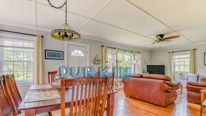 A spacious living room with a wooden dining table, leather sofa, and a ceiling fan.