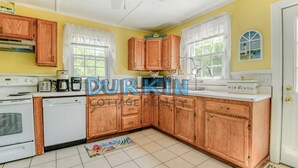 A kitchen with wooden cabinets, a white stove, and a microwave.