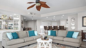Ein Wohnzimmer mit einem Zweisitzer-Sofa, einem runden Couchtisch und einem Deckenventilator.