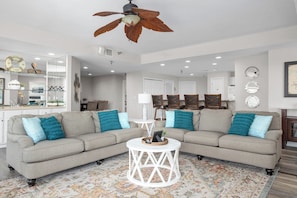 A living room with a two-seater sofa, a round coffee table, and a ceiling fan. - Towers 9106 - Four Bedroom Apartment, Sleeps 10 (Osage Beach)