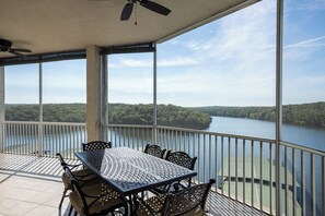 A covered outdoor area with a table and chairs, large windows, and a view of a lake. - Towers 9106 - Four Bedroom Apartment, Sleeps 10 (Osage Beach)