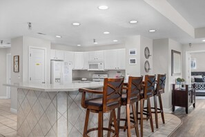 Una cocina moderna con armarios blancos, una isla central y taburetes de bar.