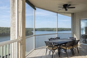 Ein Balkon mit Tisch und Stühlen, einem Deckenventilator und Blick auf einen See.