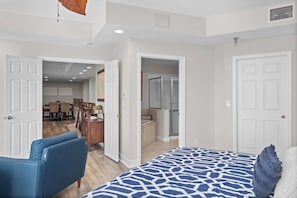 A bedroom with a bed, a blue chair, and an open door leading to a dining area. - Towers 9106 - Four Bedroom Apartment, Sleeps 10 (Osage Beach)