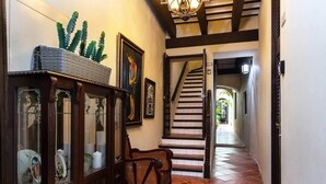 Un pasillo con un armario de madera, una silla y una escalera que lleva a otra habitación.