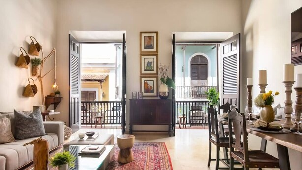 Amplia sala de estar con sofá, mesa de centro y una mesa de comedor preparada para una comida.