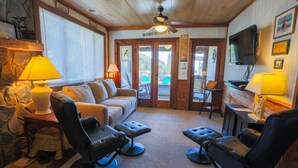 A cozy living room with a stone fireplace, a sofa, and two massage chairs. - See, Hear & Feel the Ocean from this Beach Bungalow with Private Multi-Level Deck & Swing Chair! (Folly Beach)