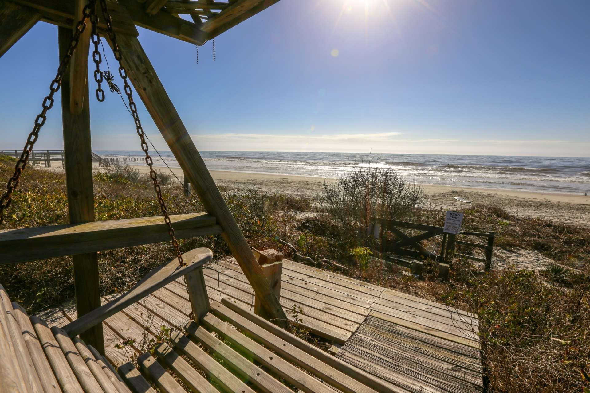 A wooden deck with a view of the beach and ocean.