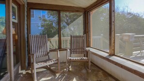 A covered patio area with two wooden chairs and a large window. - See, Hear & Feel the Ocean from this Beach Bungalow with Private Multi-Level Deck & Swing Chair! (Folly Beach)