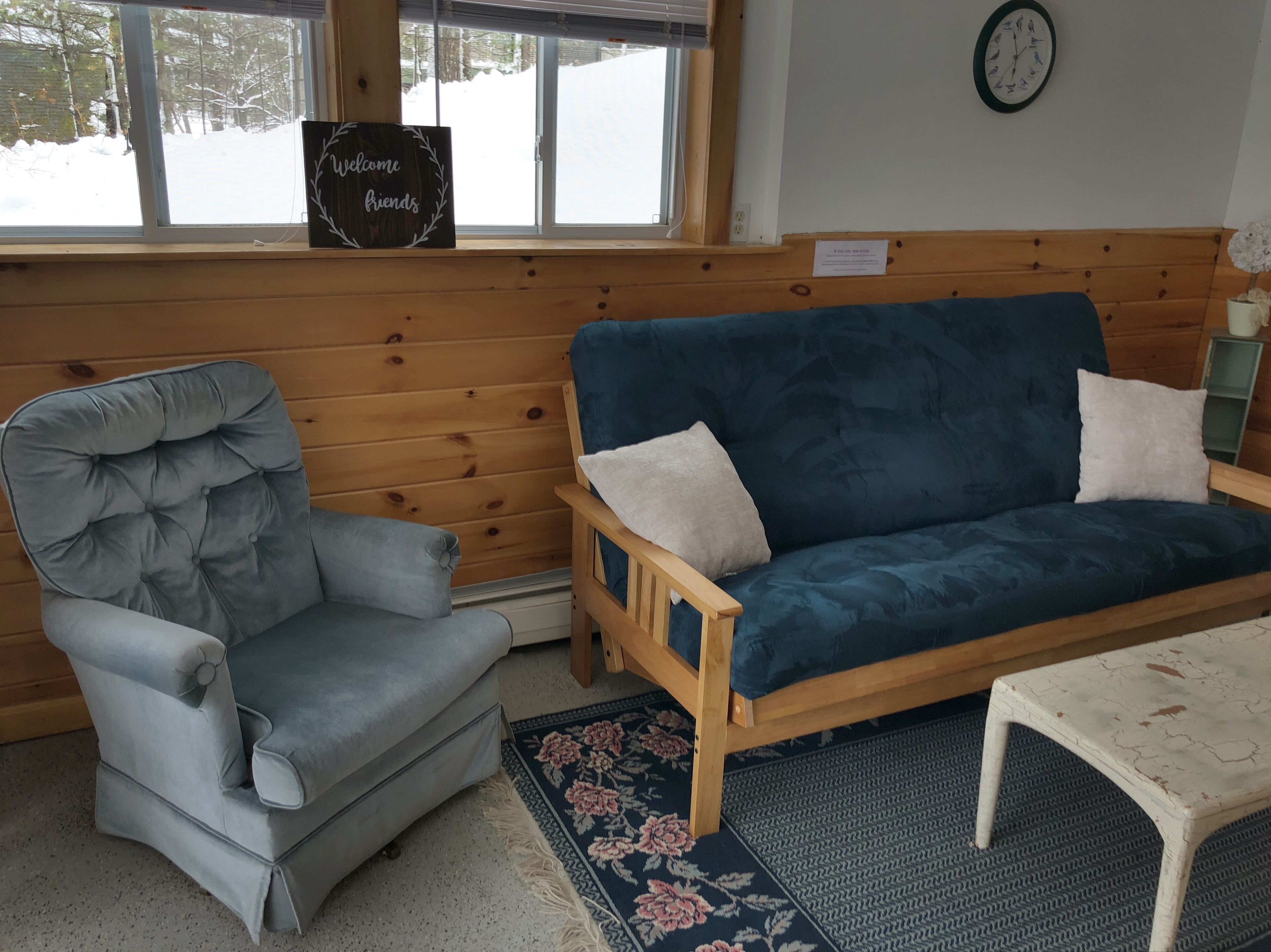 Une pièce chaleureuse avec un canapé en velours bleu, un fauteuil capitonné et une table en bois.