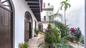 Un patio con suelo de baldosas, plantas en macetas y una puerta de madera.