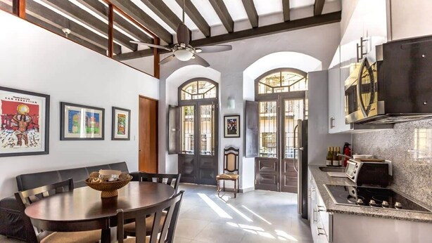 Una cocina amplia con un diseño moderno, que cuenta con una isla grande, horno empotrado y ventilador de techo.