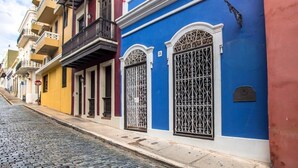 Una calle adoquinada flanqueada por edificios coloridos, cada uno con rejas y balcones ornamentales.