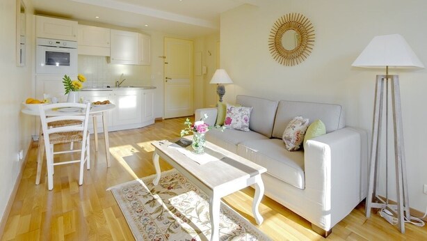 A modern living room with a white sofa, a coffee table, and a dining area with a white table and chairs. - Yasmin 1 bedroom apartment (Nice)