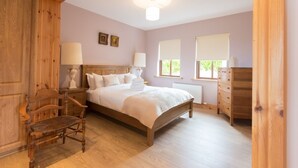 A bedroom with a wooden bed, bedside tables, a chair, and a dresser. - Ard Na Mara 4 bedroom house VRBO (Aughacasla)