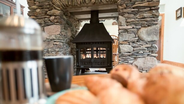 A stone fireplace with a chimney, a metal kettle, and a plate of bread. - Ard Na Mara 4 bedroom house VRBO (Aughacasla)