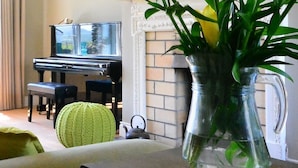Un soggiorno con un pianoforte, una poltrona verde e un vaso con piante verdi.