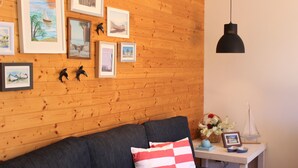 A cozy room with a wooden wall, a dark sofa, and a small table with a vase of flowers and a framed picture.
