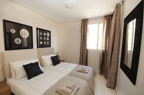A hotel room with two beds, a large mirror, and artwork on the wall.