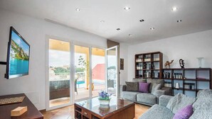 A modern living room with a sofa, coffee table, and bookshelf. There is a sliding glass door leading to an outdoor area.