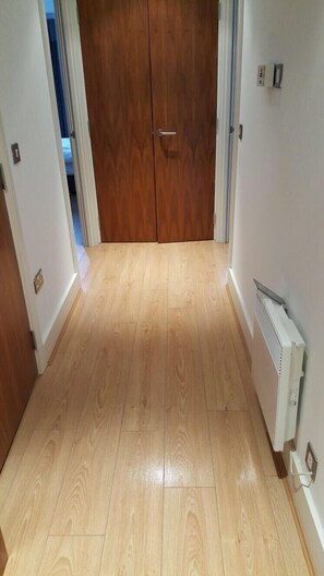 Een hal met houten vloeren, een dubbele deur en een radiator aan de muur.