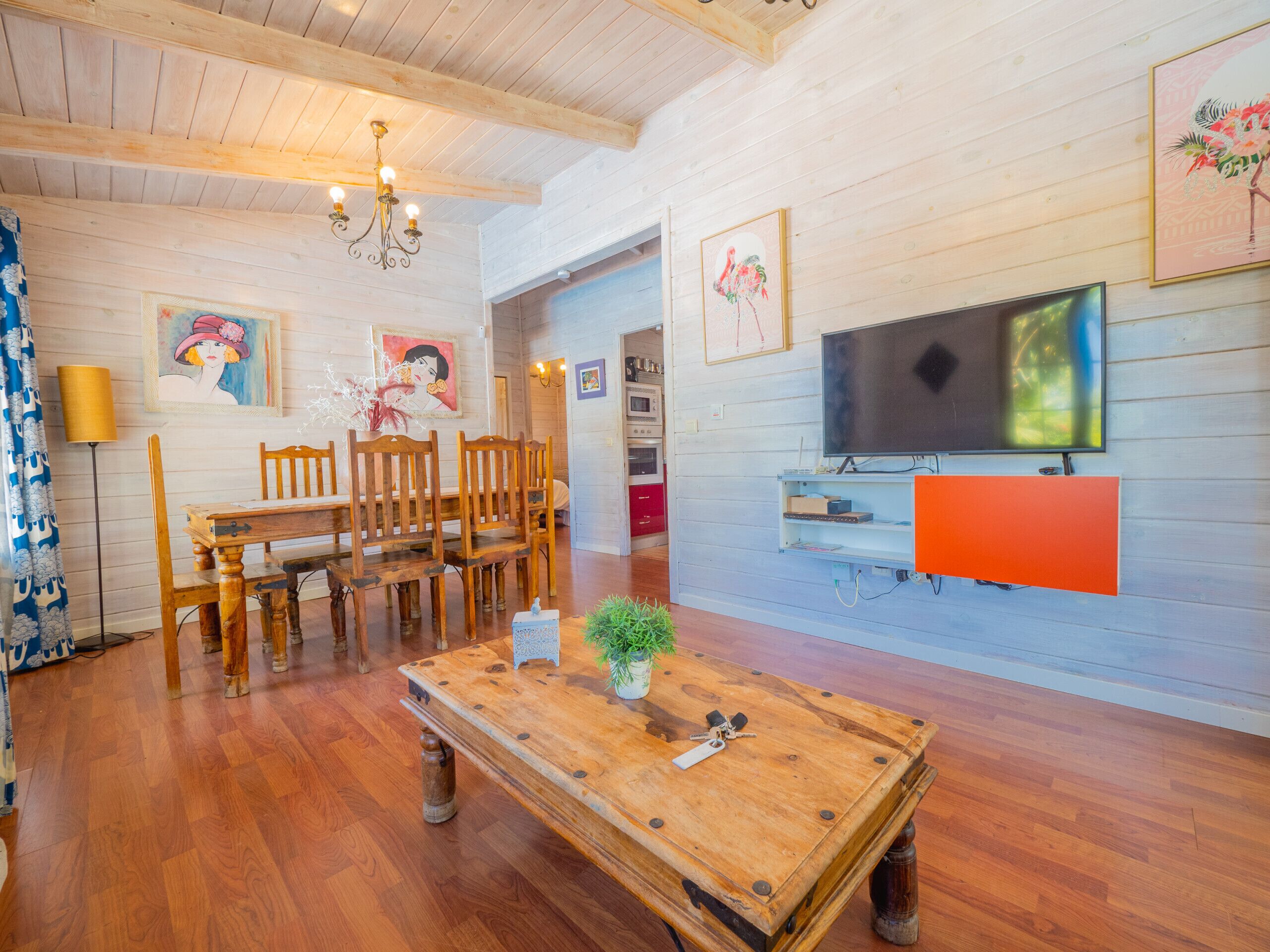 Un salon chaleureux, avec des meubles en bois, un téléviseur et des œuvres d’art accrochées aux murs.