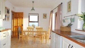 Una cocina con una mesa y sillas, un lavabo y armarios.