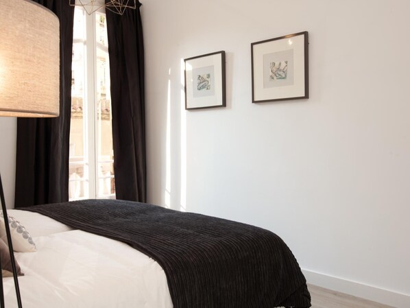 A bedroom with a bed, a lamp, and two framed pictures on the wall. - Stylish apartment in city center 22 (Barcelona)