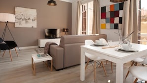 En moderne stue med sofa, spisebord og fjernsyn.
