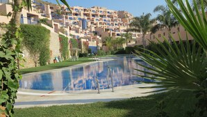 A swimming pool surrounded by greenery and a residential building in the background. - TOPLIGGING: Luxury penthouse, golf, terrace 180 ° fantastic sea view, free Wifi (Mojácar)