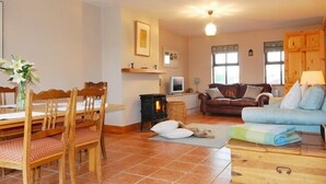 Ein gemütliches Wohnzimmer mit Kamin, einem Essbereich mit Holzsesseln und einer Couch.