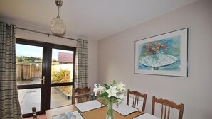 Ein Essbereich mit einem Tisch für vier Personen, einer Blumenvase und einem Gemälde an der Wand.