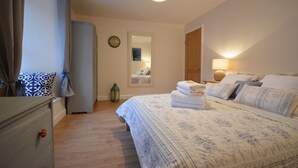 A bedroom with a bed, bedside table, lamp, and a mirror on the wall. - Morning Side 4 bedroom house VRBO (Dingle Peninsula)