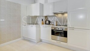 A modern kitchen with white cabinetry, a stainless steel oven, and a built-in microwave. - Minuet - 1 bedroom apartment (Nice)
