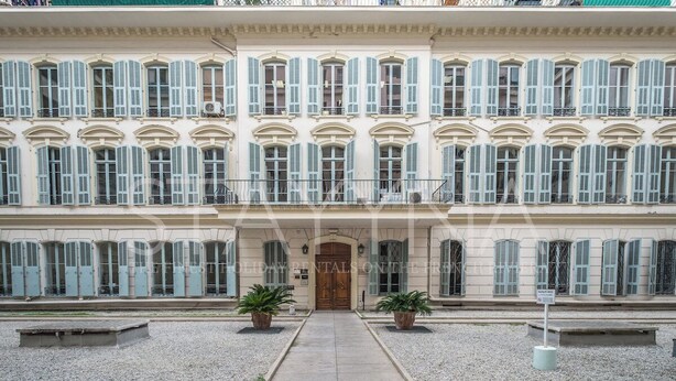 Un edificio imponente in stile classico, con facciata simmetrica, numerose finestre con persiane e un ingresso centrale.