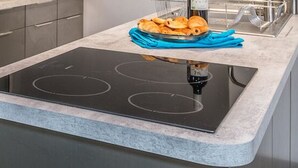 Una cucina moderna con piano cottura integrato, elettrodomestici in acciaio inossidabile e un ripiano con un asciugamano blu e un piatto di pasticcini.