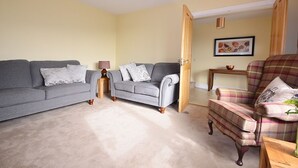 A living room with two sofas, a chair, a small table, and a door leading to another room. - Ceann Scribe 5 bedroom house VRBO (Dingle Peninsula)