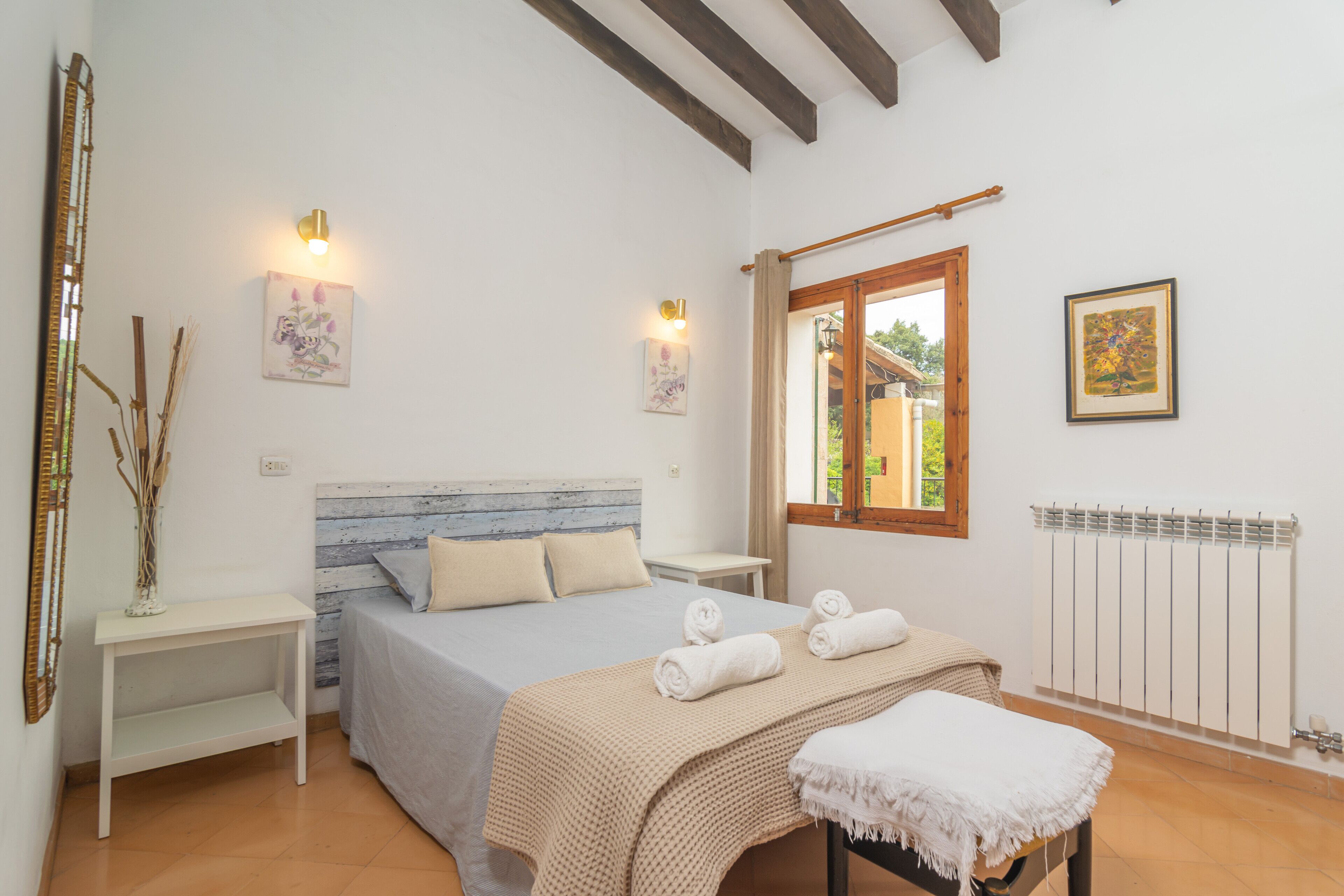 A bedroom with a bed, bedside tables, a window, and a radiator.