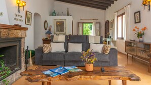 A cozy living room with a fireplace, a sofa, a coffee table, and a bookshelf. - CASA MIRANDA - Chalet with terrace in Valldemosa. Free WiFi (Valldemossa)