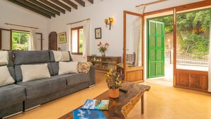 A spacious living room with a grey sofa, wooden coffee table, and a view of the garden through a sliding glass door. - CASA MIRANDA - Chalet with terrace in Valldemosa. Free WiFi (Valldemossa)