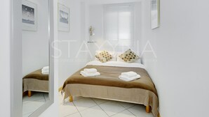 Ett modernt hotellrum med en stor säng, en spegel och inramade tavlor på väggen.
